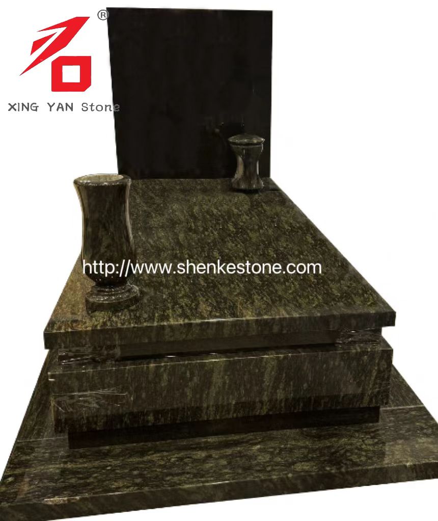 Olivgrön granitmonument och stödjande svarta stentabletter, vaser och lyktor